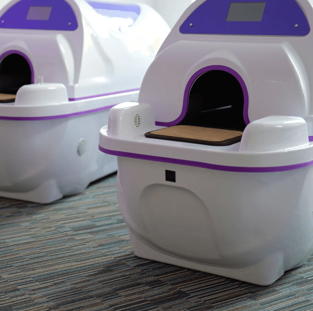 Two Regen Pods with canopies closed in a clinic room, jade bed visible at the opening